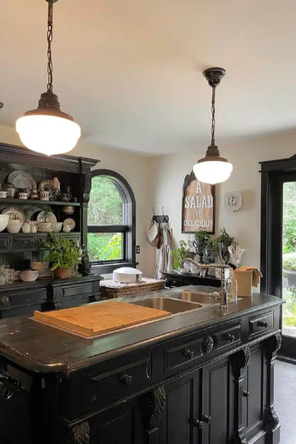 Vintage milk glass pendant lights from @marketofstars illuminating dark green kitchen island with bronze chain details.