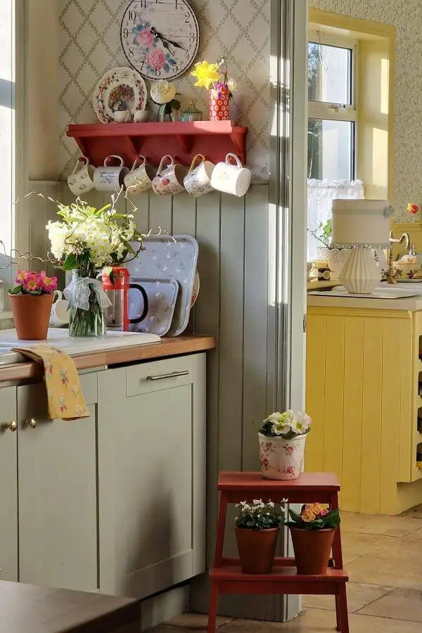 Colorful vintage teacup display from @cooneynest featuring floral patterns on red floating shelf with cottage charm.