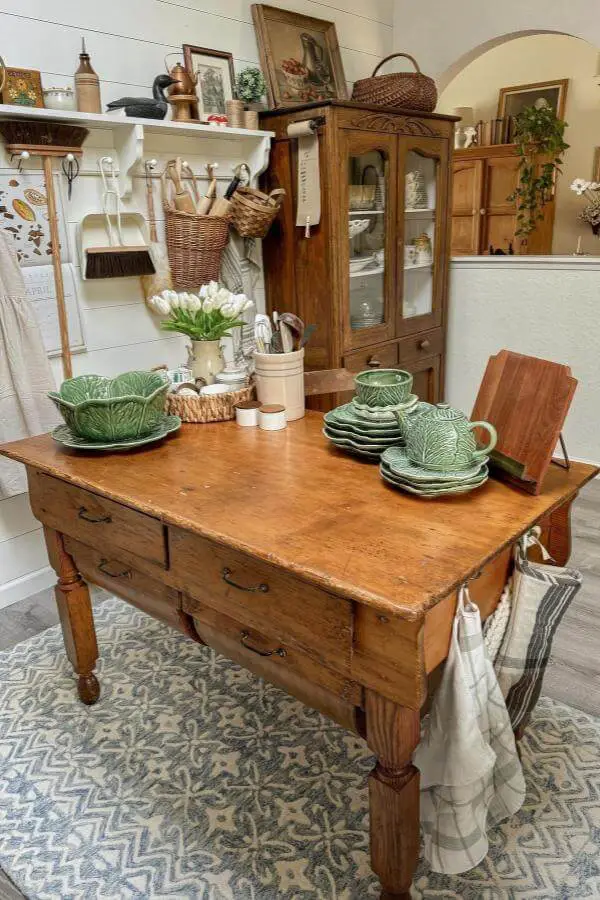 Sage green cabbage leaf ceramic dishes from @mamahensteph. Vintage-style dinnerware displayed on rustic wooden kitchen island.
