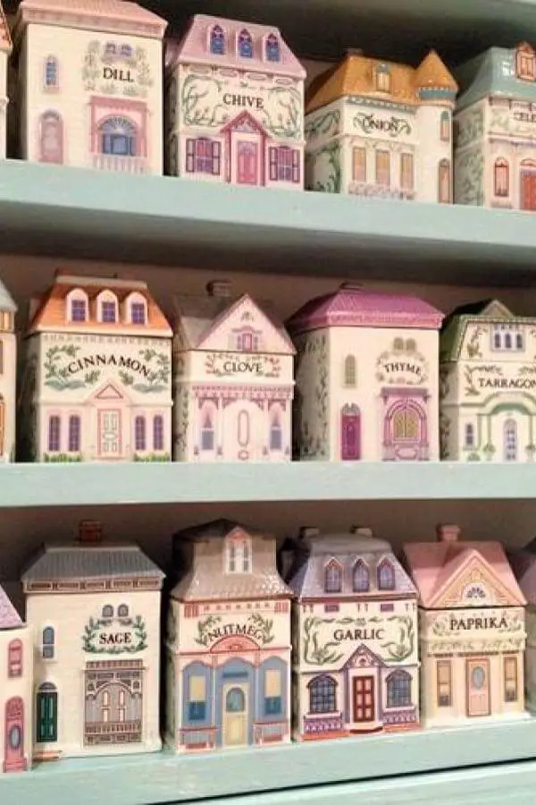 Painted house-shaped spice containers from Bustle and Stew featuring pastel colors and vintage architectural details on pantry shelves.