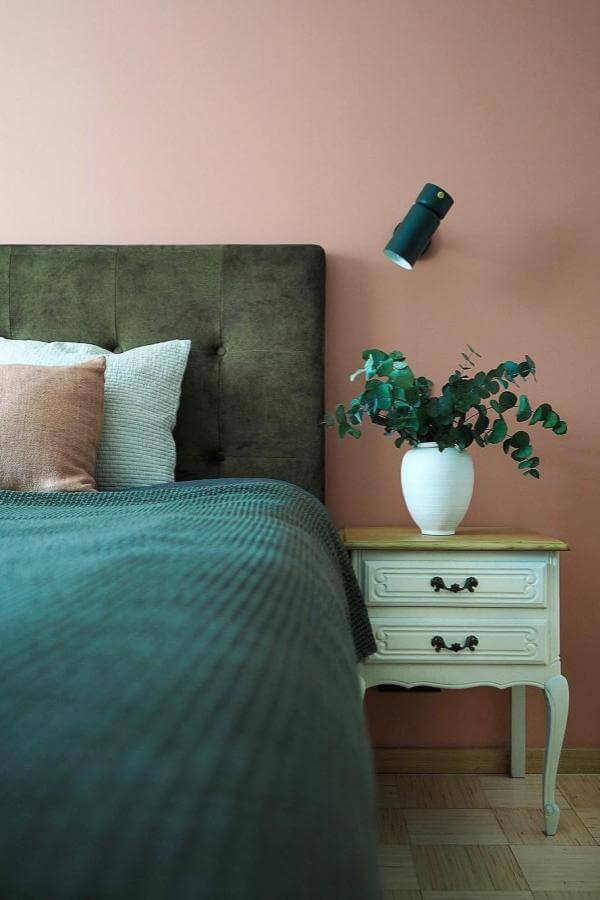 Vintage wood nightstand from @triinuaruoja.interiors with lush green accents, perfect for cozy bedroom styling.