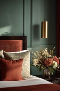 Glam gold pendant lighting in green and terracotta bedroom steals the scene with warm, elegant glow.