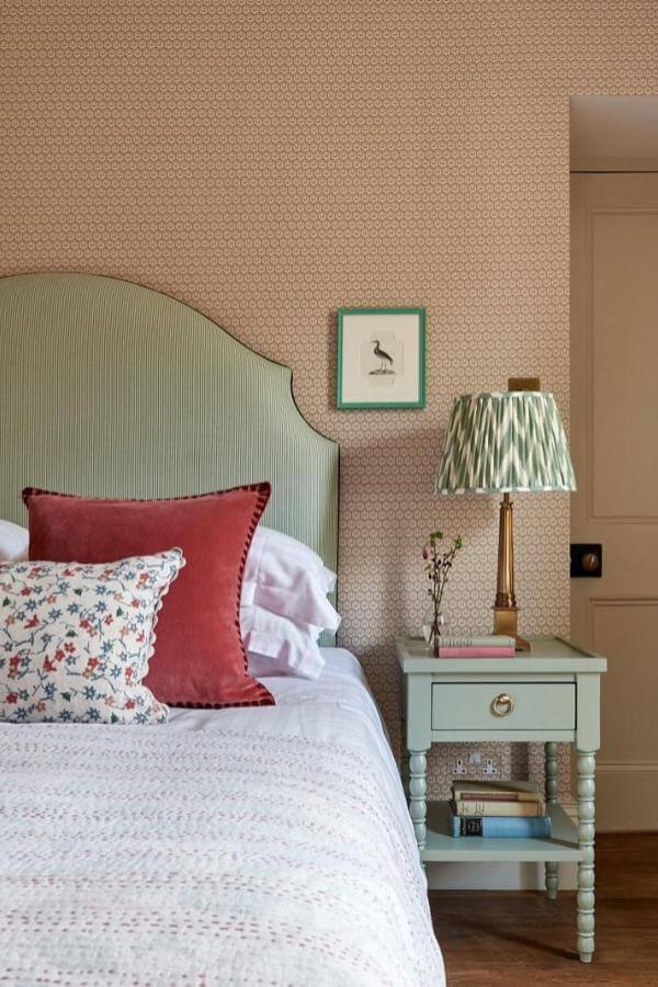 Curved green upholstered headboard with patterned textures in a green and terracotta bedroom from @johnstonparkeinteriors. Elegant warmth.