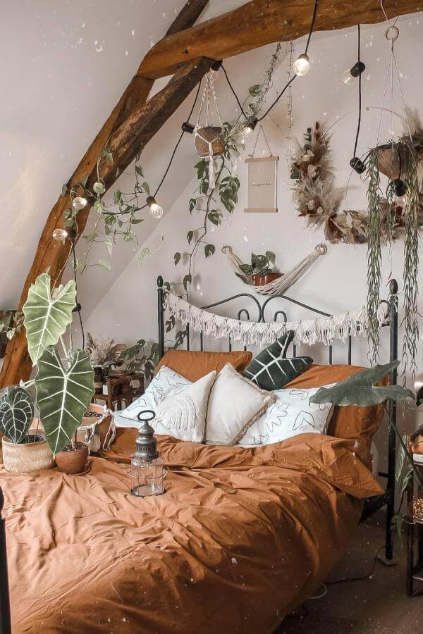Lush green plants and warm terracotta accents in a cozy rafter bedroom from @traqueuse.green. Jungle-inspired calm.