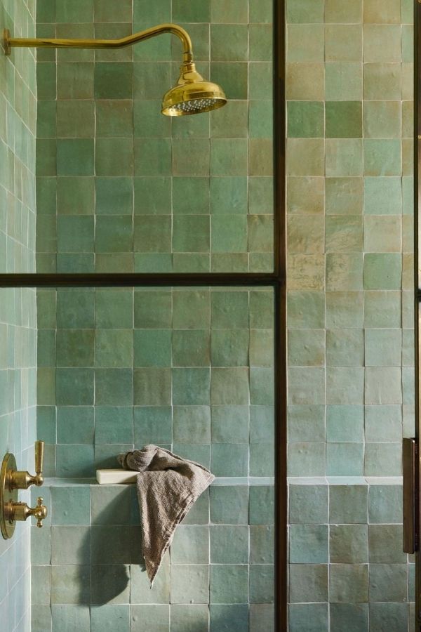 Lush green bathroom with brass fixtures, exemplifying green bathroom ideas.