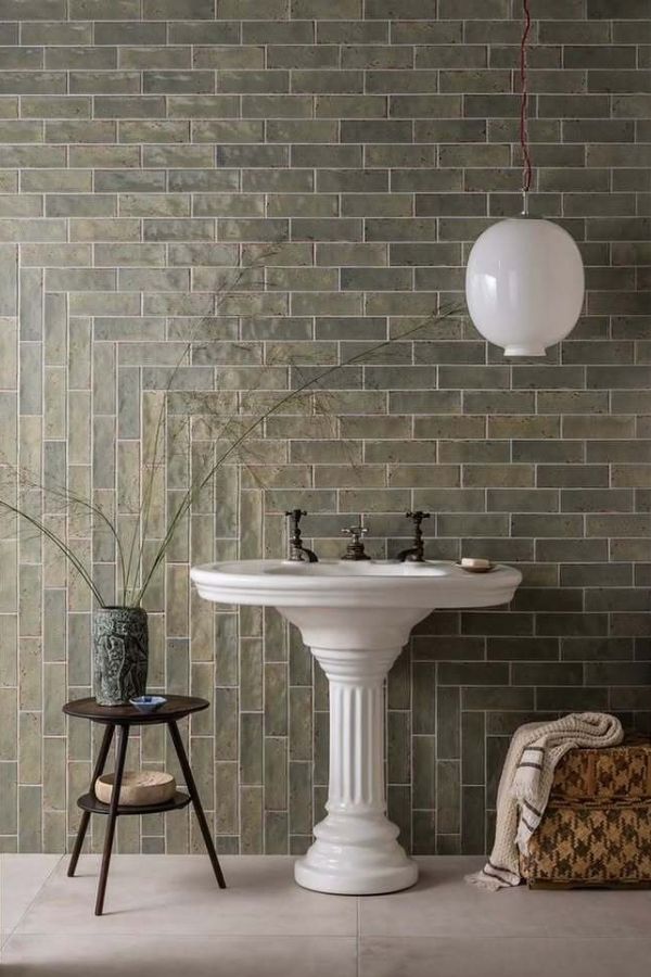 Olive tiles and high-contrast sink highlight green bathroom ideas.