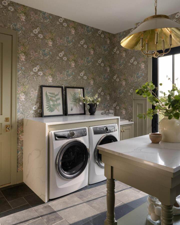 lush green botanical wallpaper laundry room with green cabinets and brass light from @sarahshieldsphoto. Cozy stylish green laundry room ideas with floral accents and marble countertop