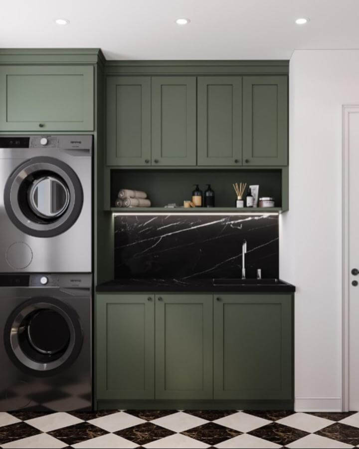 Olive green cabinetry laundry room with black marble backsplash and checkered flooring from @nextleveldesigning. Stylish green laundry room ideas.