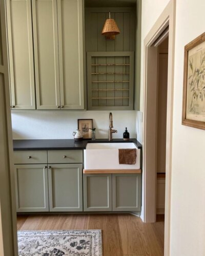 soft sage green cabinetry laundry room from @seventhdaydesign calm and cozy green laundry room ideas with vintage brass accents