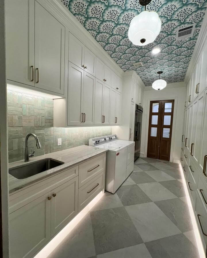 Soft green tile backsplash laundry room from @angiestithdesigns with patterned ceiling and under-cabinet lighting in green laundry room ideas style.