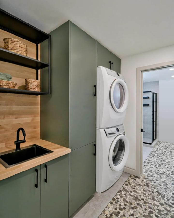 Green matte cabinets and wood countertop laundry room from @shanardesign with black fixtures and patterned tile floor creating fresh green laundry room ideas.