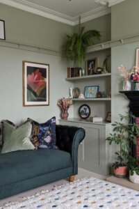 Warm wood open shelving from @ohmyedwardian showcasing statement decor for a stylish green living room.