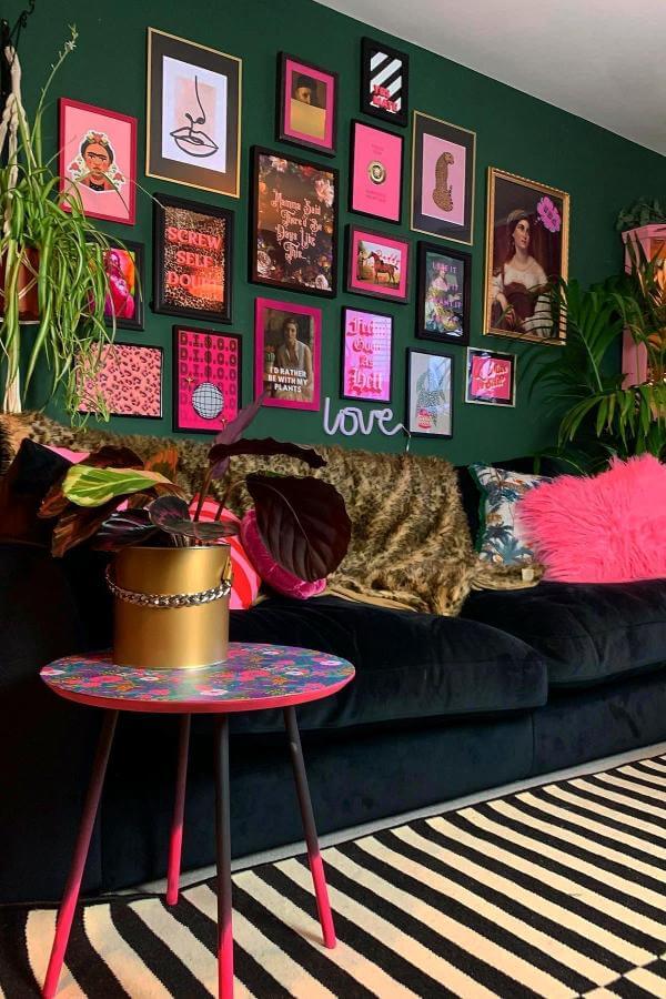 Vibrant pink accents on gallery wall in cozy living room from @homeofgetkooky. Bold art enhances green living room space.