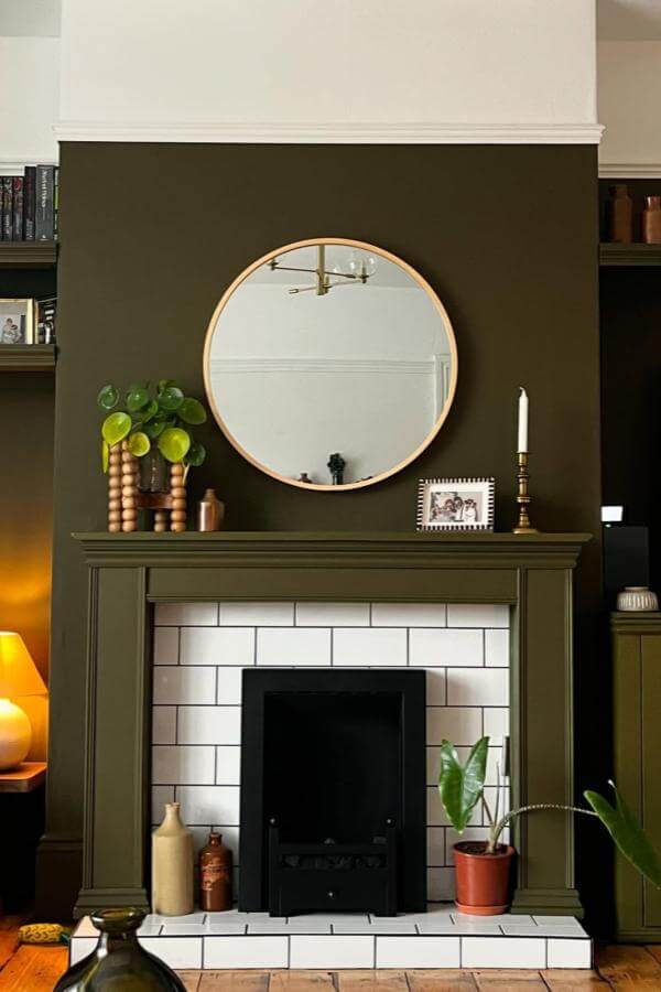 Moody green fireplace with sleek round mirror from @that_1880s_house. Cozy focal point for a sophisticated living space.