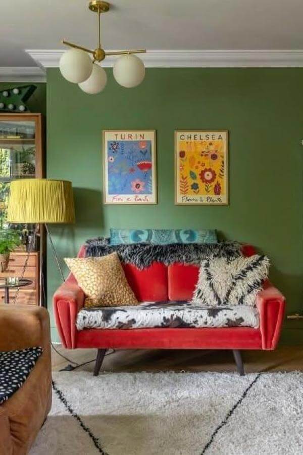 Vibrant red sofa in green living room from @emmaigannon. Bold color contrasts with lush greenery.