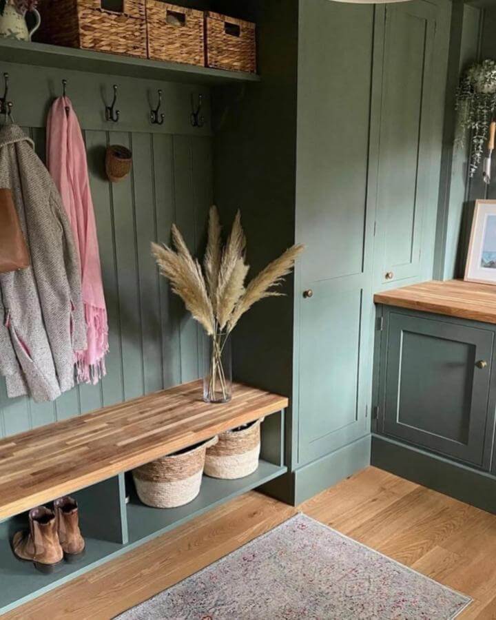 Natural sage green mudroom with wood bench and woven baskets by @theblankcanvashome featuring cozy organized entryway elements.