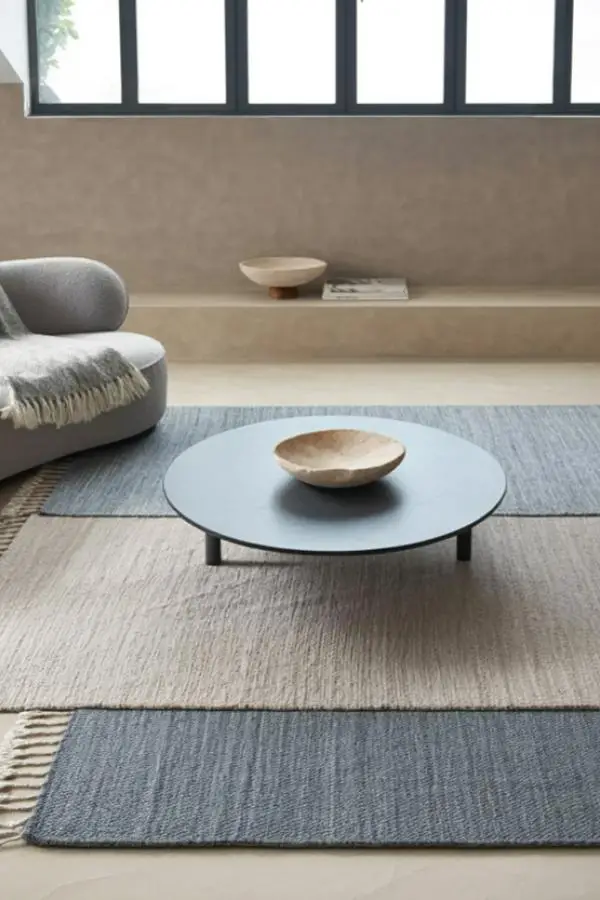Layered textured rugs in neutral tones showcasing grey minimalist living room ideas with clean lines and natural materials.