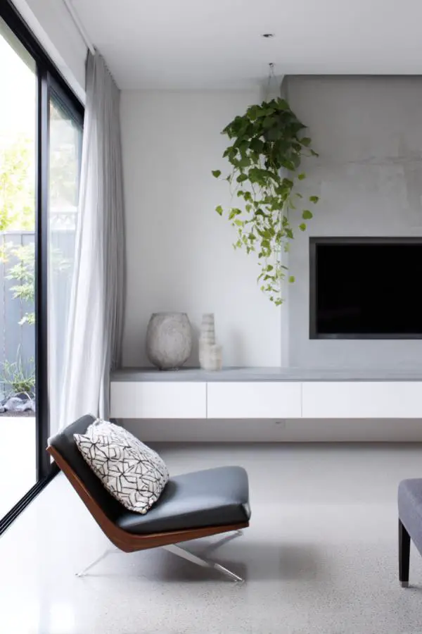 Modern floating media console demonstrating grey minimalist living room ideas with trailing greenery accent.