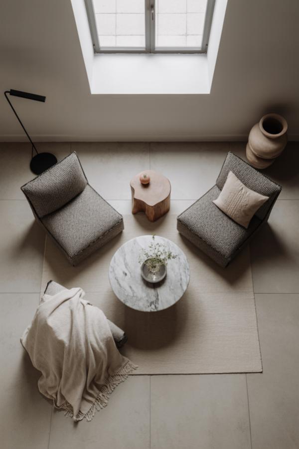Overhead view of modern living room with grey chairs, marble table, and skylight above neutral tiled flooring.