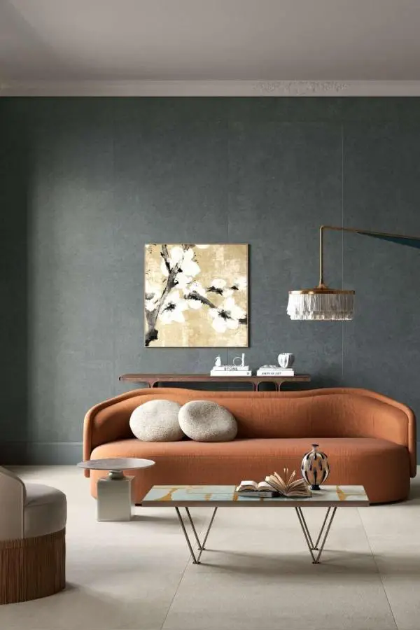 Curved orange sofa against sage green accent wall from @laminam_uk. Clean minimal styling with neutral accessories.