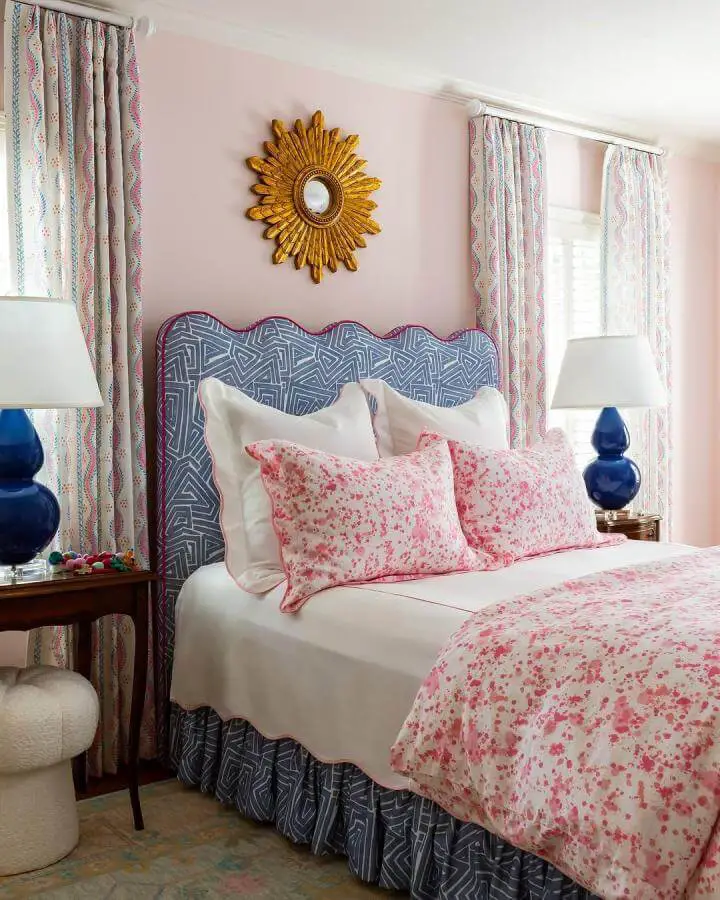Navy blue geometric headboard from @lacefield.designs showcasing grown woman bedroom ideas with pink floral bedding and gold sunburst mirror.