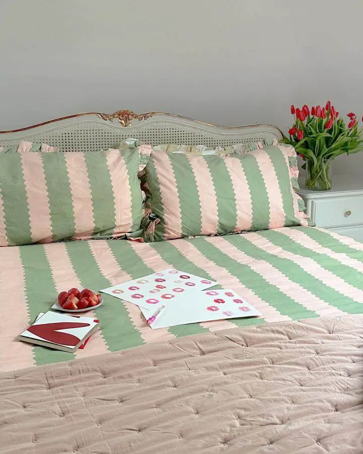 Mint green and pink striped bedding from @frenchbedroom. Vintage French cane headboard with fresh tulips and quilted throw.