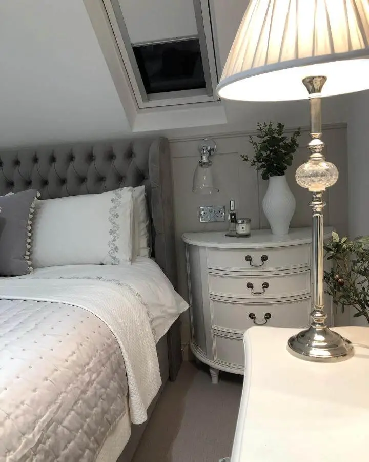 Curved grey nightstand from @overton_renovation_. Features three drawers with brass handles in cozy attic bedroom setting.