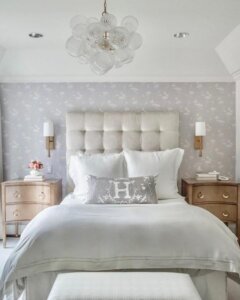 Transparent glass bubble chandelier from @lpearsondesign. Modern organic lighting fixture suspended above neutral tufted headboard.