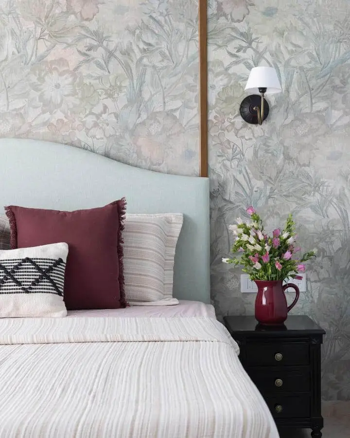Tropical botanical wallpaper bedroom from @attirail.in. Sage headboard with burgundy accents and striped bedding.
