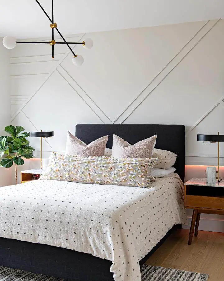 Modern bedroom featuring geometric white wall molding grown woman bedroom ideas from @odettedesigngroup. Dark headboard with contemporary lighting fixtures.