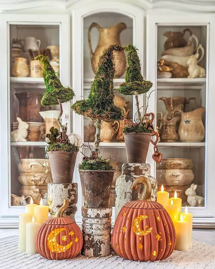 Moss topiary display from @corbelcottage showcasing creative halloween centerpiece ideas with carved pumpkins and candles.
