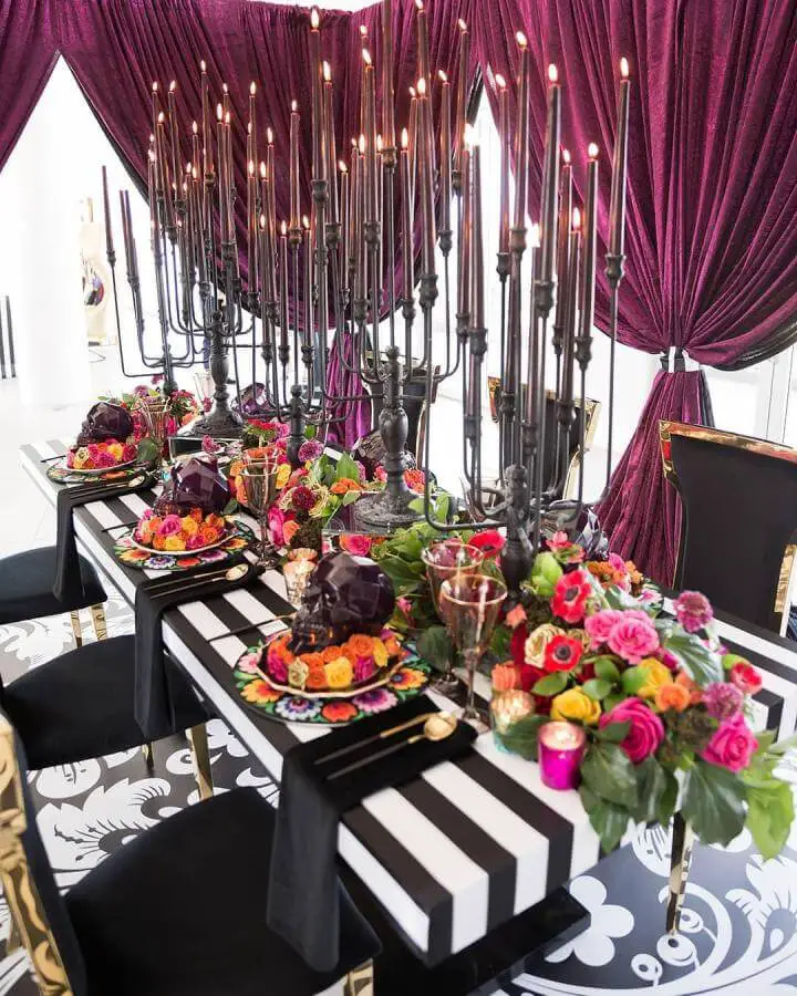 Dramatic burgundy velvet dining setup from @partyslate. Black candelabras and colorful florals create gothic elegance.