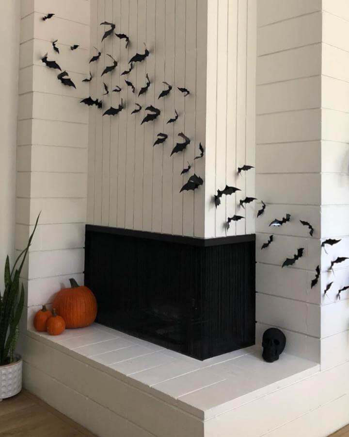 Black paper bat swarm fireplace from @mid_mod_la_mesa showcasing creative halloween fireplace decor ideas with white shiplap walls.