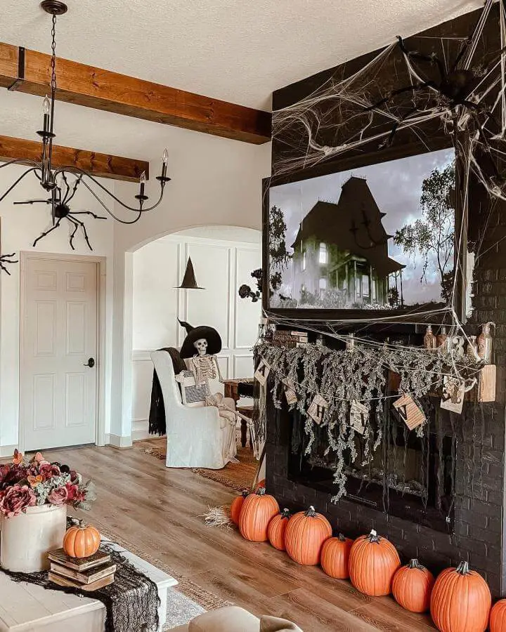 Dark brick fireplace from @ashtonsedita with cobwebs, pumpkins and spooky TV display creating dramatic seasonal atmosphere.