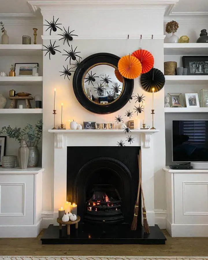 Festive paper fan display above white fireplace from @ginandinteriors. Orange and black decorations with spider accents.
