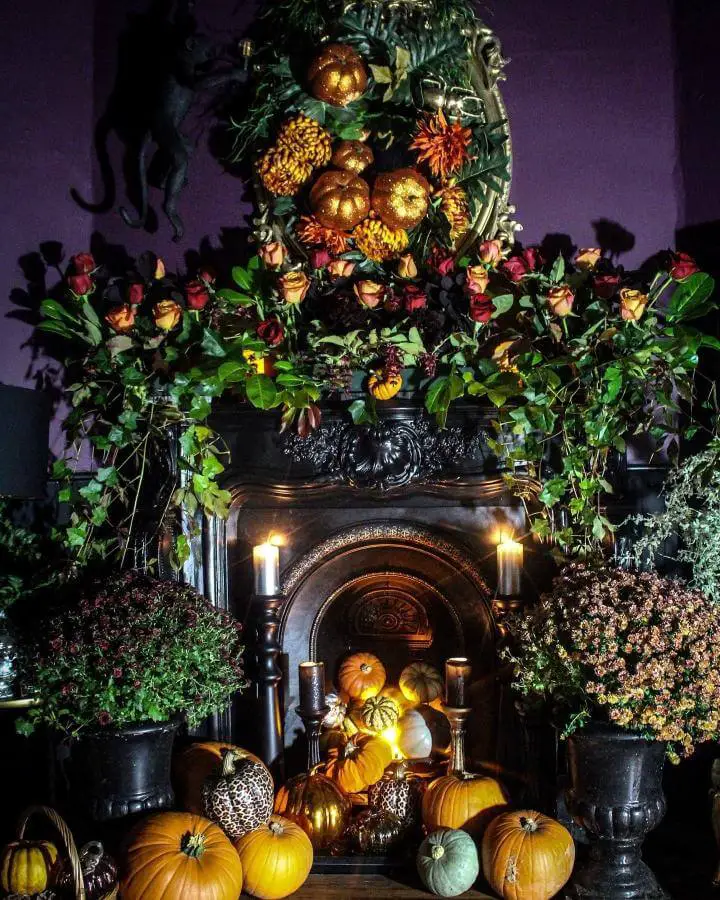 Dark rose garland mantel from @couthyhome showcasing elegant halloween fireplace decor ideas with pumpkins and moody lighting.