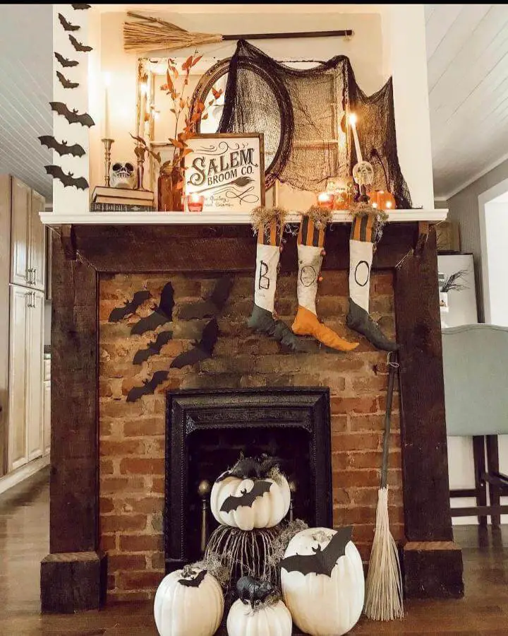 Spooky mantel display with black paper bats and white pumpkins showcasing creative halloween fireplace decor ideas from @thefinleyfarmhouse.