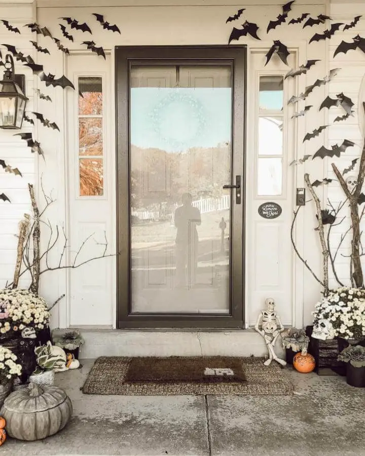 Black paper bat cutouts from @kaylum_sher. Swarming across white porch walls in spooky flight pattern.