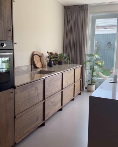light wood paneled kitchen cabinetry and neutral interiors from @koakdesign with plants and sleek faucet in calm kitchen space