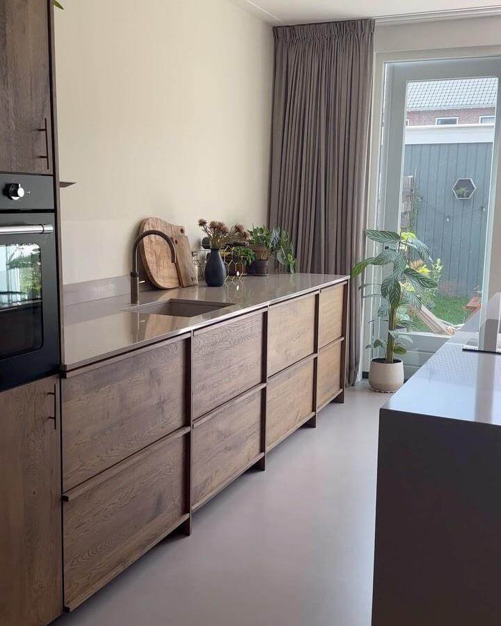 light wood paneled kitchen cabinetry and neutral interiors from @koakdesign with plants and sleek faucet in calm kitchen space