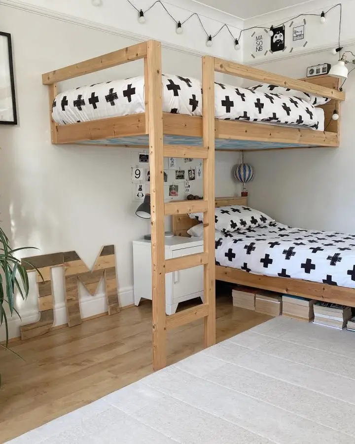 Natural wood floating bunk bed setup from @sambramley.cc. Modern corner bedroom design with black cross pattern bedding.