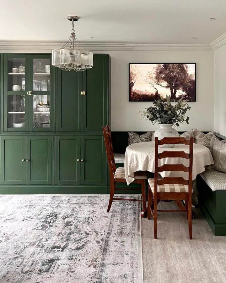 Forest green painted dining room cabinet from @maxine.home. Glass doors display white dishware.