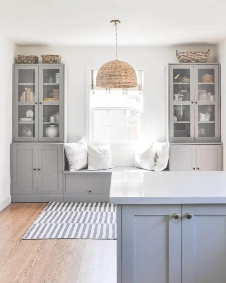 Gray painted cabinet storage from @hydrangeatreehouse with built-in window seat and wicker basket styling.