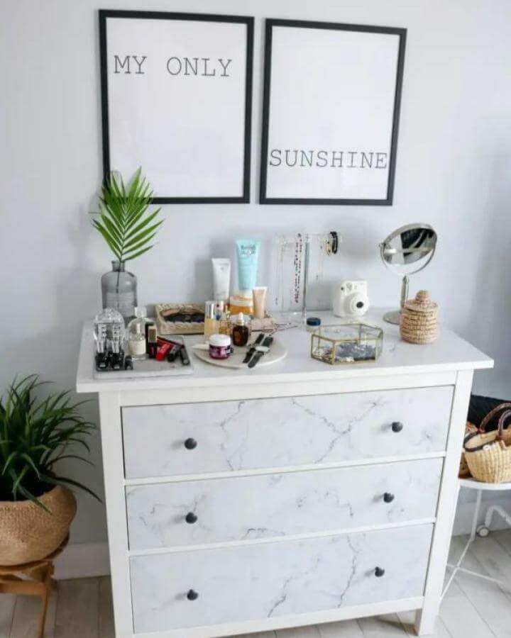 White marble contact paper covered Ikea Hemnes dresser with black knobs and simple decor from Petite and Bold creating a clean stylish bedroom look.