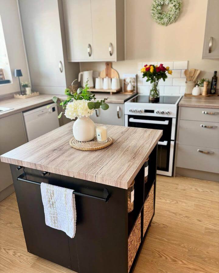 black and woodgrain kitchen island from @sjw.home with storage baskets and towel rail enhancing small kitchen utility