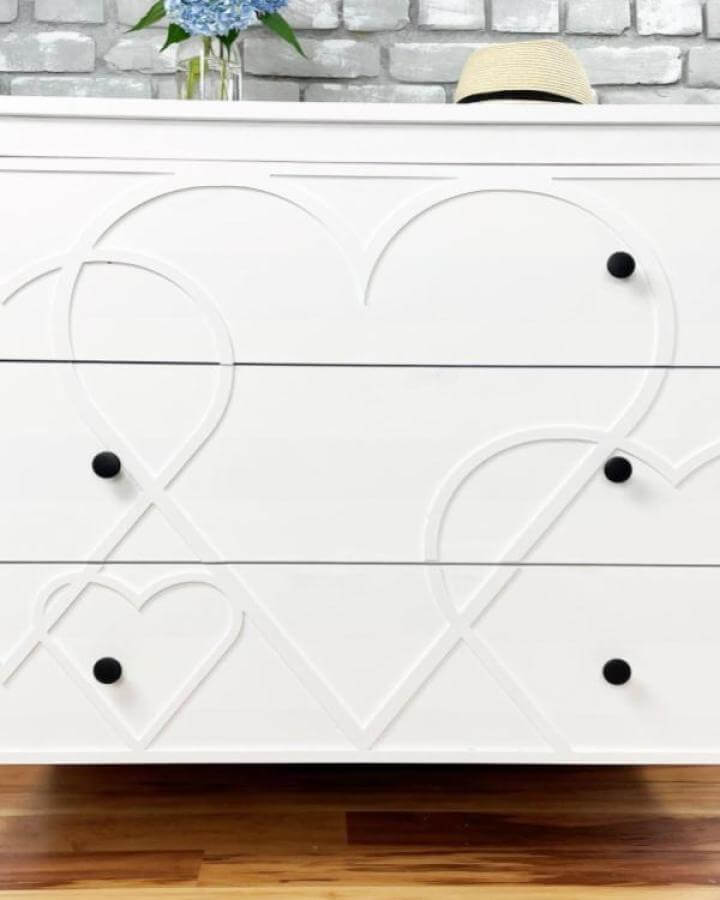 White heart-patterned Ikea Koppang dresser with black knobs and wood strip accents from @myoverlays. Charming textured furniture makeover.