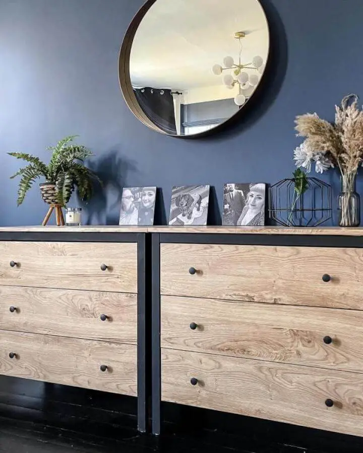 Natural oak drawer fronts and black hardware on dressers with deep blue wall background from @fromblandtofab. Ikea koppang hacks in a modern cozy room.