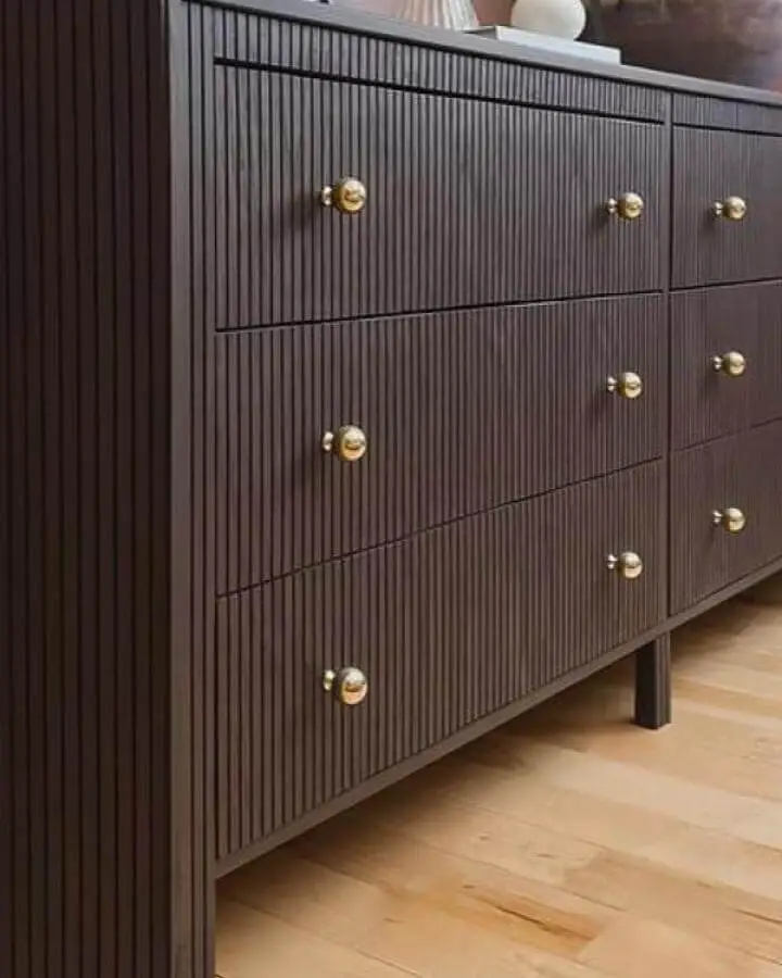 Dark wood dresser with vertical grooves and brass knobs from Peony + Honey showing elegant ikea koppang hacks.