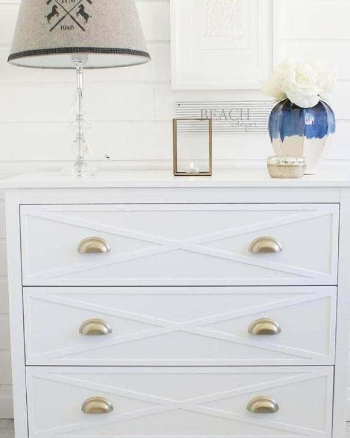 White X-trimmed Ikea Koppang dresser with gold handles and coastal-inspired decor from @panelove.pl. Simple elegant hack.