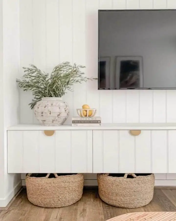 White floating media console with brass handles and woven baskets from The Interiors Addict in a cozy living room ikea media center hacks & ideas.